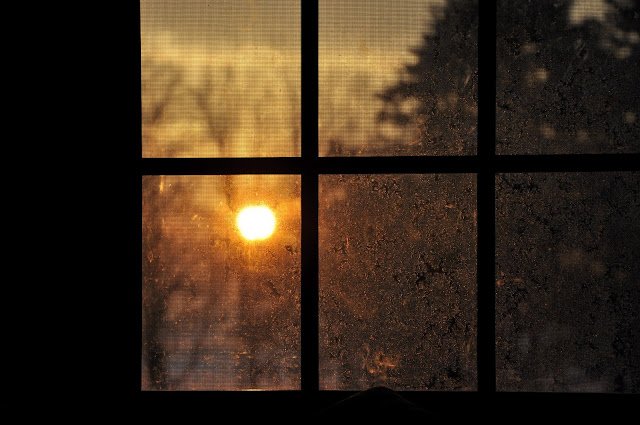 cross in window with sun in background 