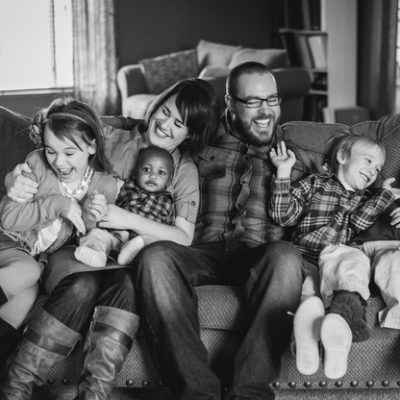 Family laughing on couch by Alyssa and Drew Photography