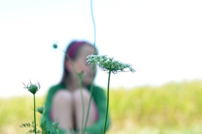 Girl looking in distance with flower in focus by Katie M. Reid Photogprahyflower in focus by Katie M. Reid Photography