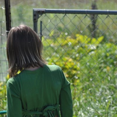 Girl walking through gate to garden by Katie M. Reid