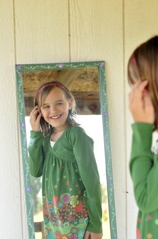 Girl looking in mirror and smiling by Katie M. Reid photography 