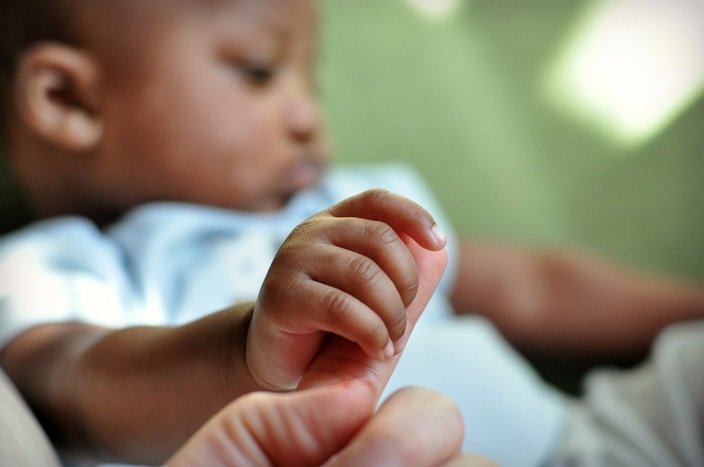 Mother holding son's finger by Katie M. Reid Photography